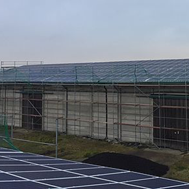 Eingerüstete Halle mit Photovoltaik-Anlage auf dem Dach.