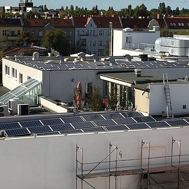 Photovoltaikanlage auf einem Industrieflachdach, innerstädtisch, mit anderen Häusern herum